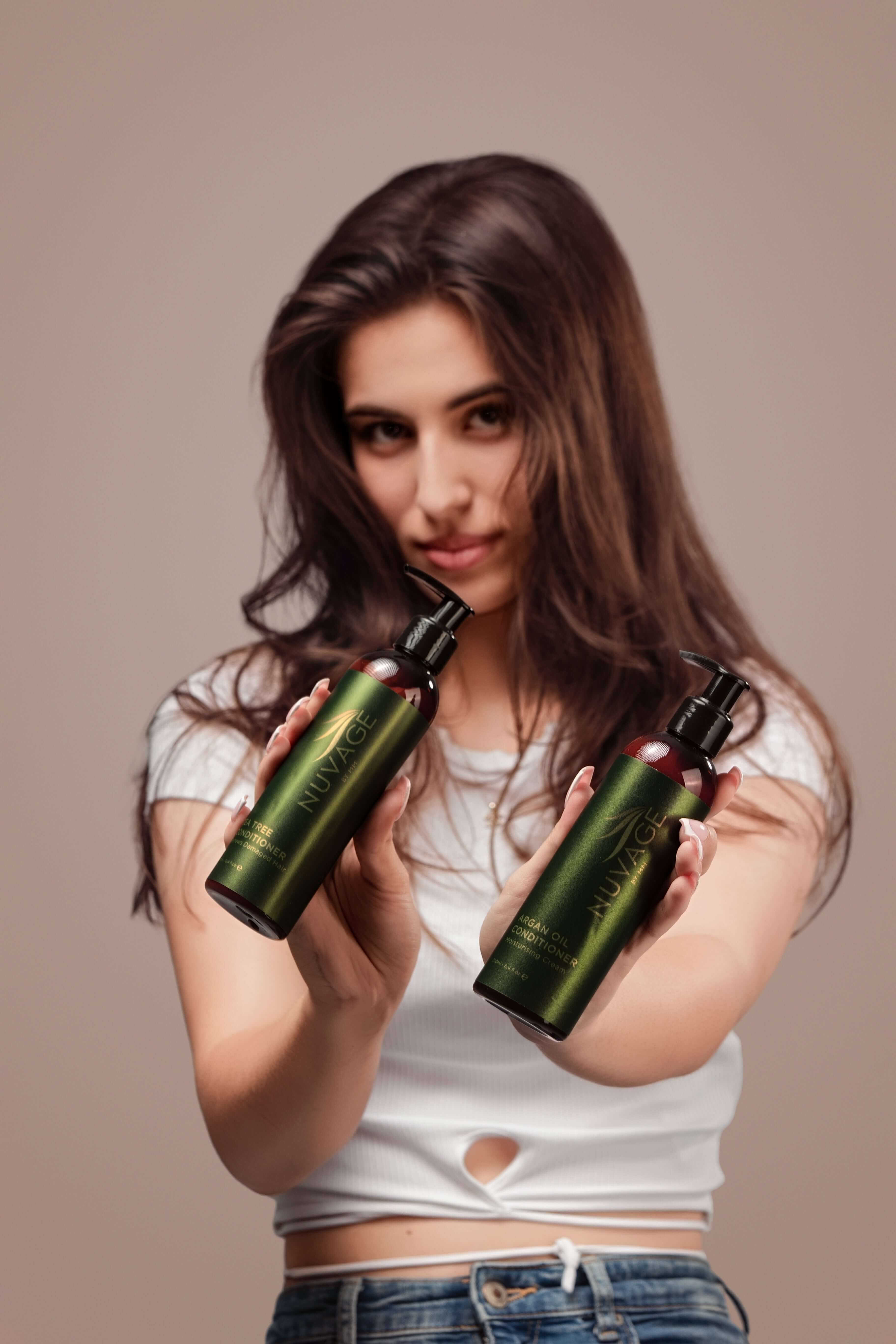 A model holding bottles of Daily Shampoo - Body&Hair, showcasing its dual cleansing benefits for hair and skin.