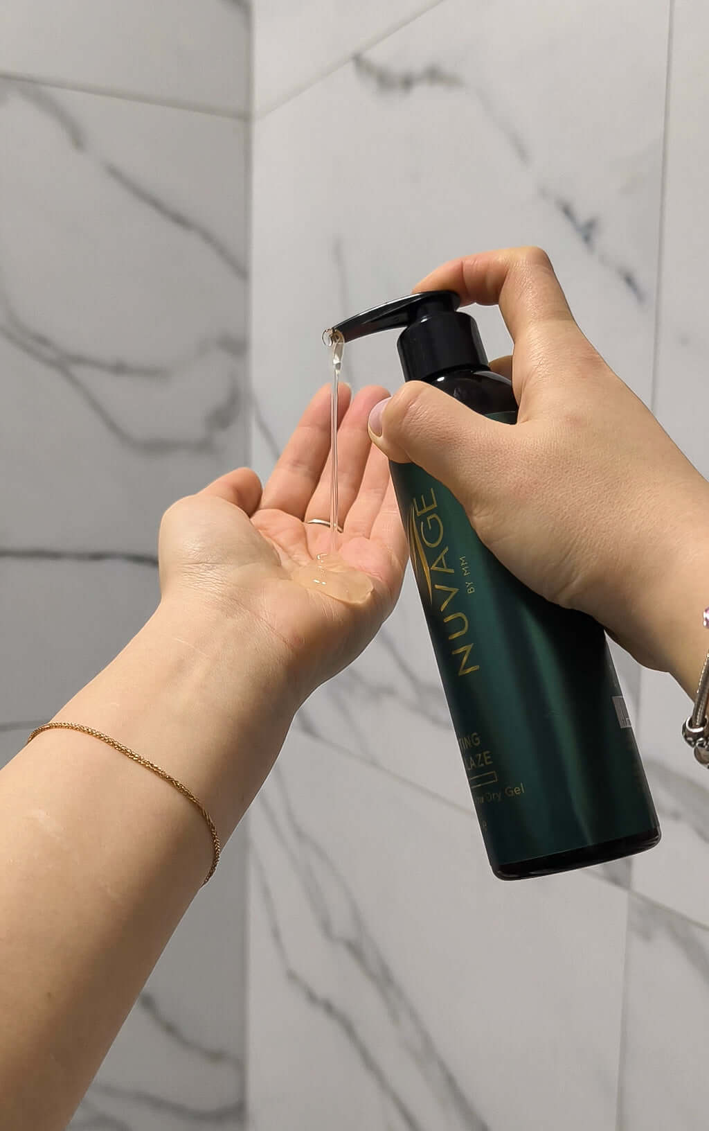 Nuvage Sculpting Hair Glaze 250ml being dispensed from a bottle into a hand in a bathroom setting.