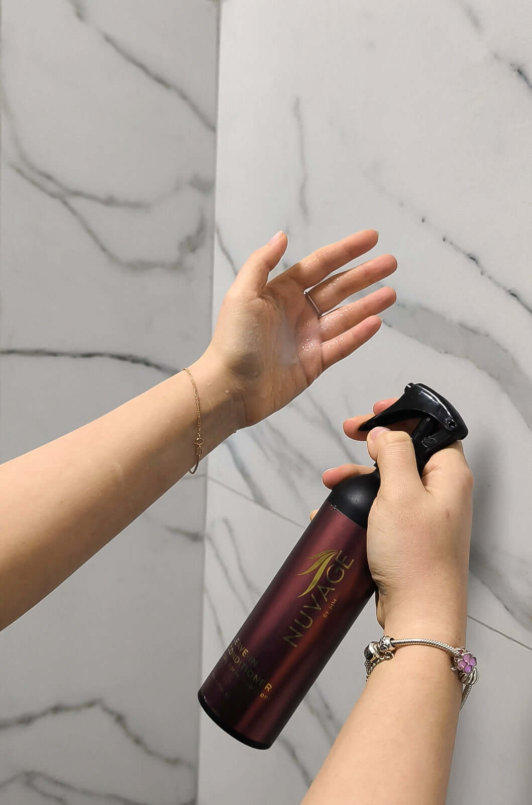 Nuvage Leave In Conditioner bottle being sprayed onto hair for easy detangling and added shine.